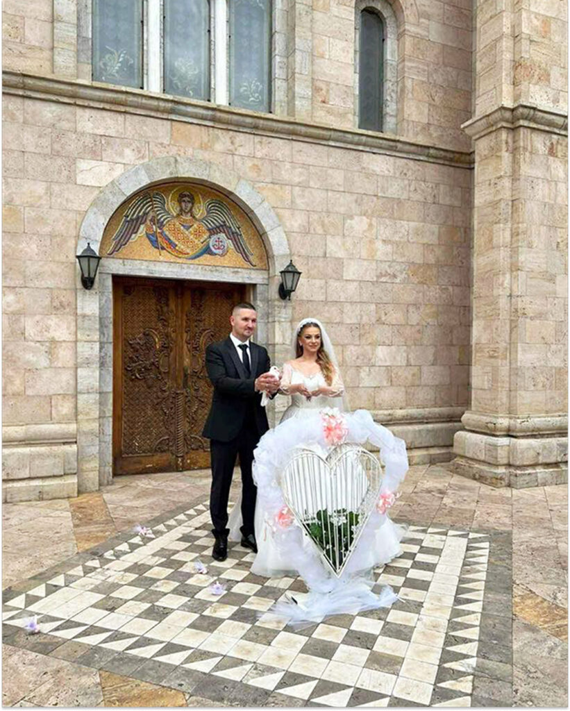 Romanticen moment so beli gulabi na mladenci pred crkva.