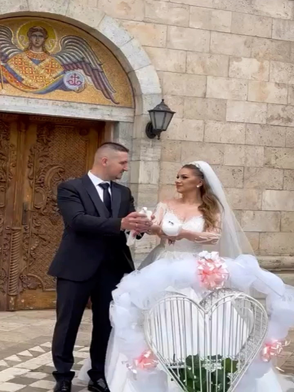 Romanticen moment so beli gulabi na mladenci pred crkva.